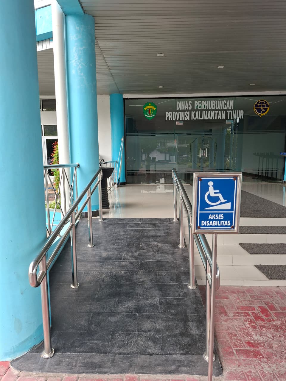 Ram akses disabilitas pada pintu masuk utama Kantor Dinas Perhubungan Provinsi Kalimantan Timur, dilengkapi rambu bergambar kursi roda bertuliskan Akses Disabilitas.